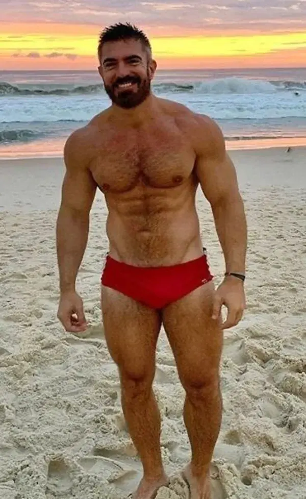 Handsome hot hunk in red swimwear beach pose
