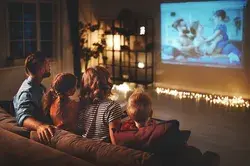 family mother father and children watching projector, TV, movies with popcorn in the evening   at home