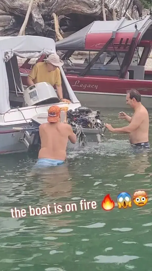 Boat engine is on fire and people are trying everything to put it out