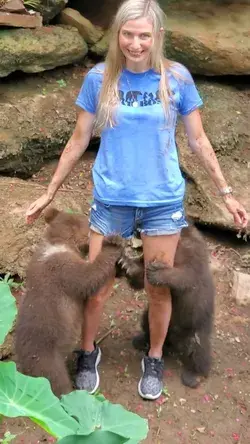 Girl has two baby bears sucking on her legs