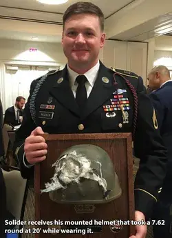 Soldier displays the battered helmet that saved his life during an insider attack in Afghanistan...